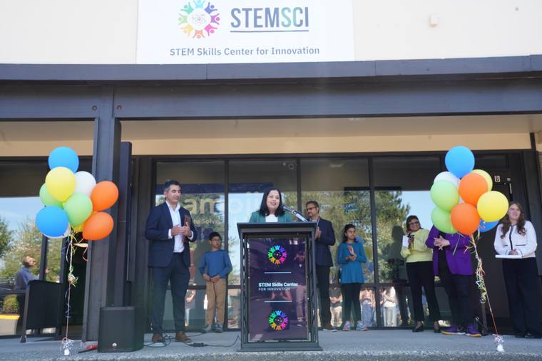 A speaker addresses the crowd as students and staff look on